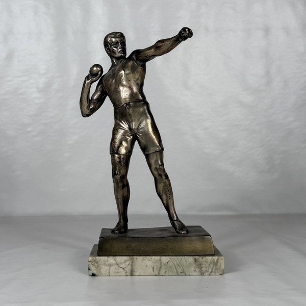 Skulptur på stensockel, kulstötare, mässing.